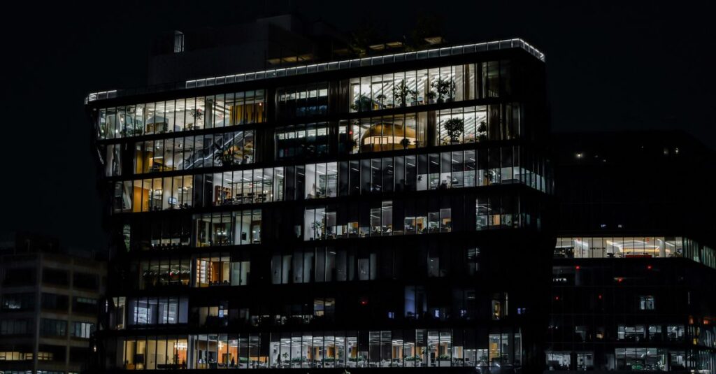 A captivating image of a contemporary office building illuminated against the night sky, showcasing urban architecture.