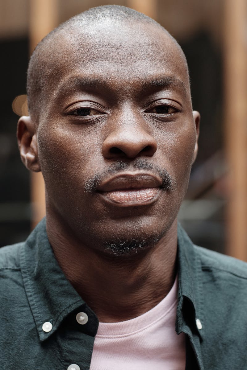 Close-up portrait of a stylish, confident man in an outdoor setting.